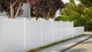 Solid white vinyl fence next to sidewalk