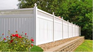 White vinyl fence with red flowers next to it 